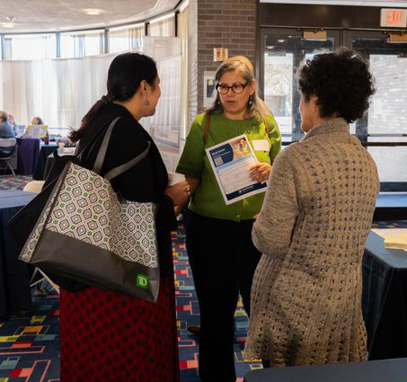 Rosalie Girau, Director of The Bridge Fund of Westchester, and Executive Director Maria Toledo share program information with a summit attendee.